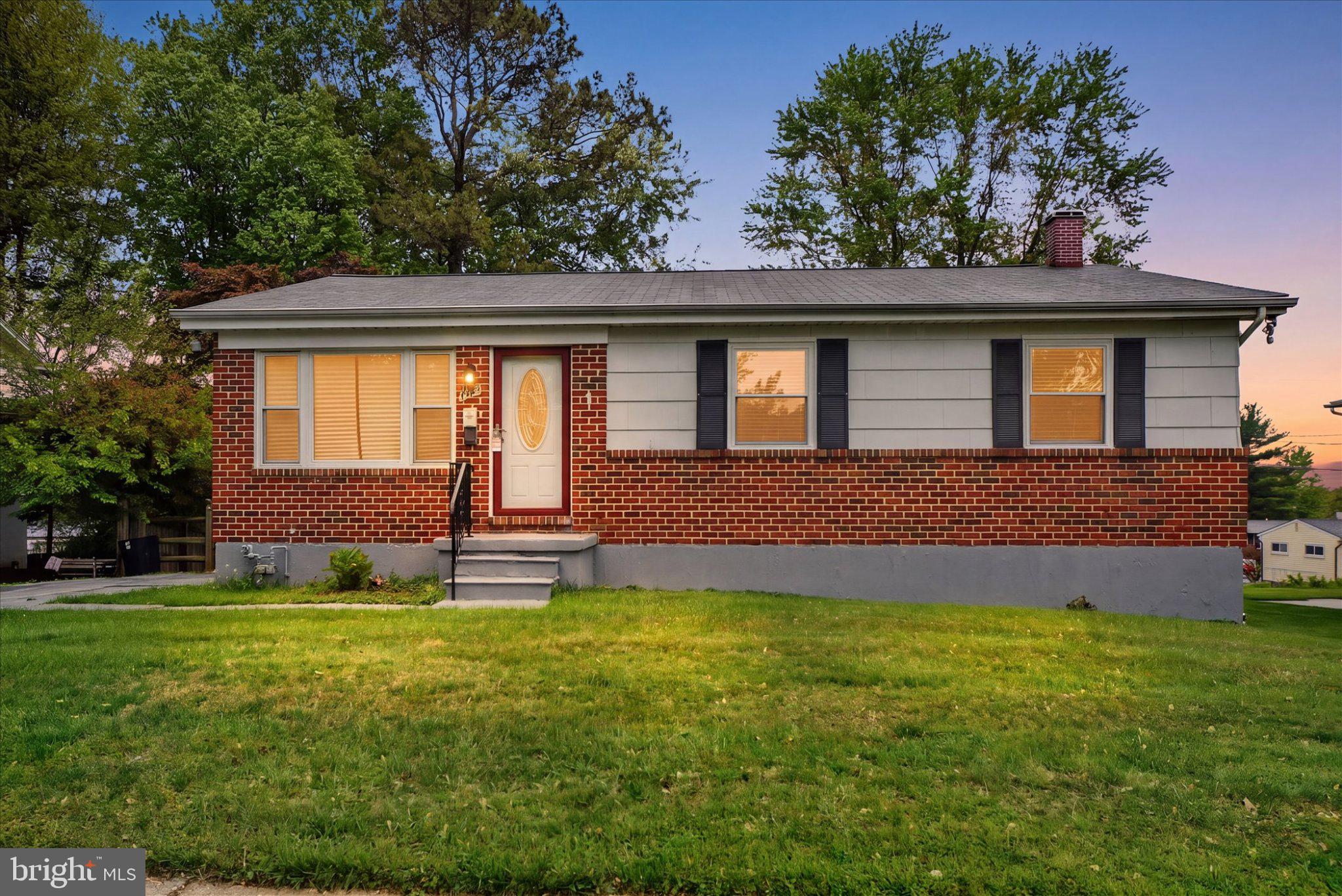a front view of house with yard and trees in the background