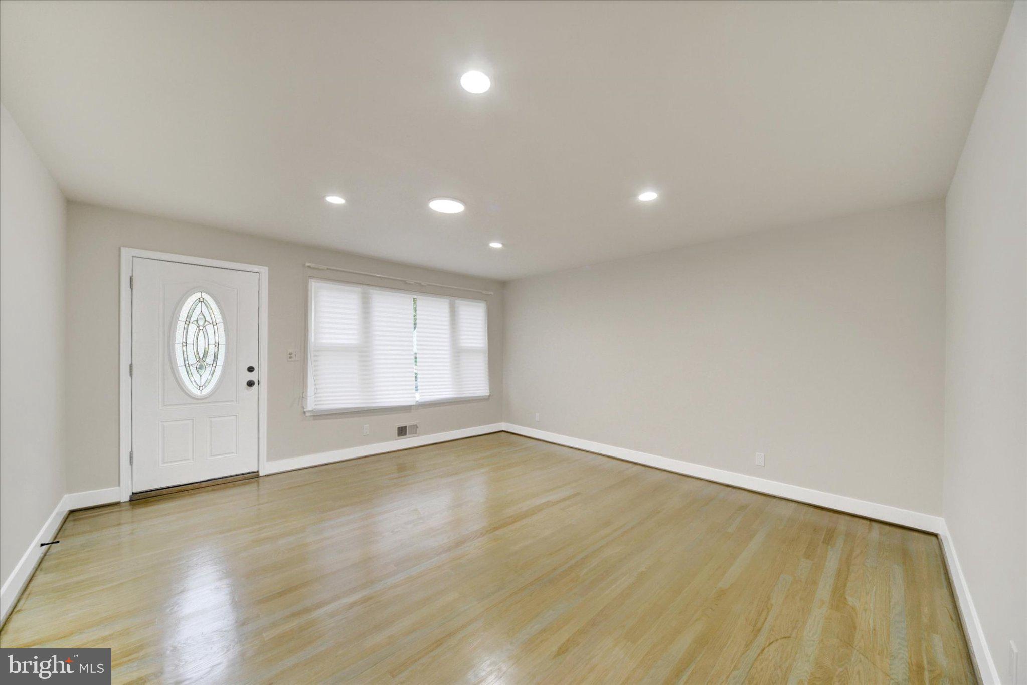 3709 Lamoine Road Randallstown, MD 21133 - Photo 4 of 25 a view of an empty room with a window and wooden floor