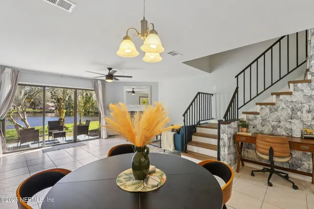 a view of a dining room with furniture a chandelier and large windows
