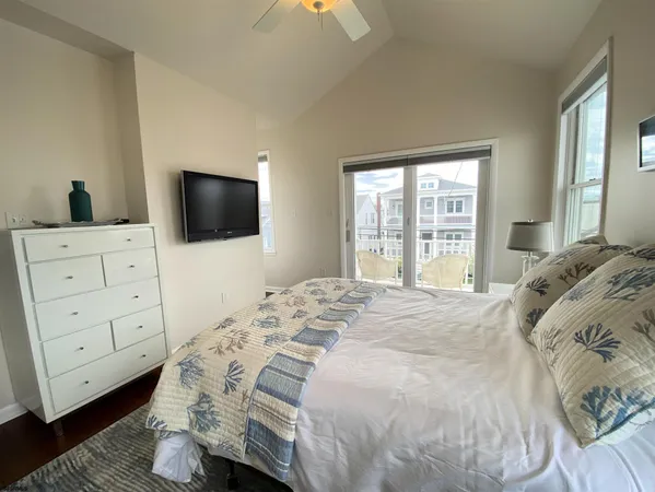 a bedroom with a bed and a flat tv screen on dresser