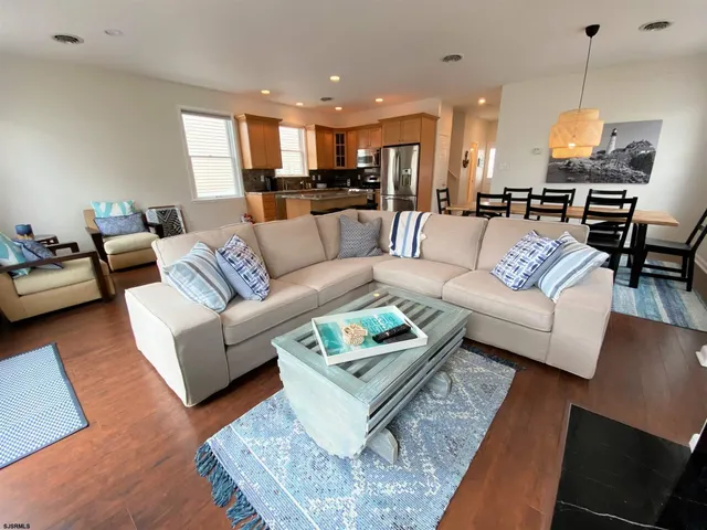 a living room with furniture kitchen view and a wooden floor