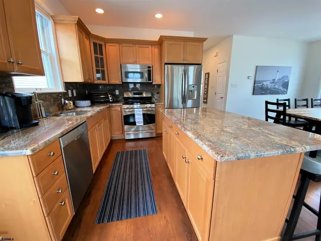 a kitchen with stainless steel appliances a refrigerator a sink a stove a microwave and cabinets