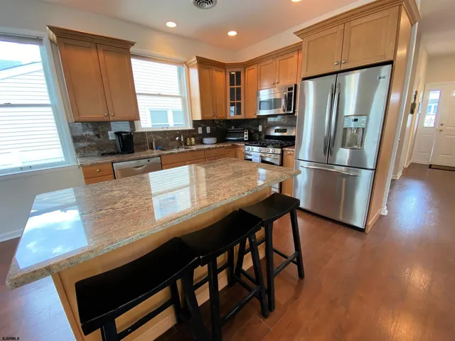 a kitchen with stainless steel appliances granite countertop a refrigerator a stove a sink and a refrigerator