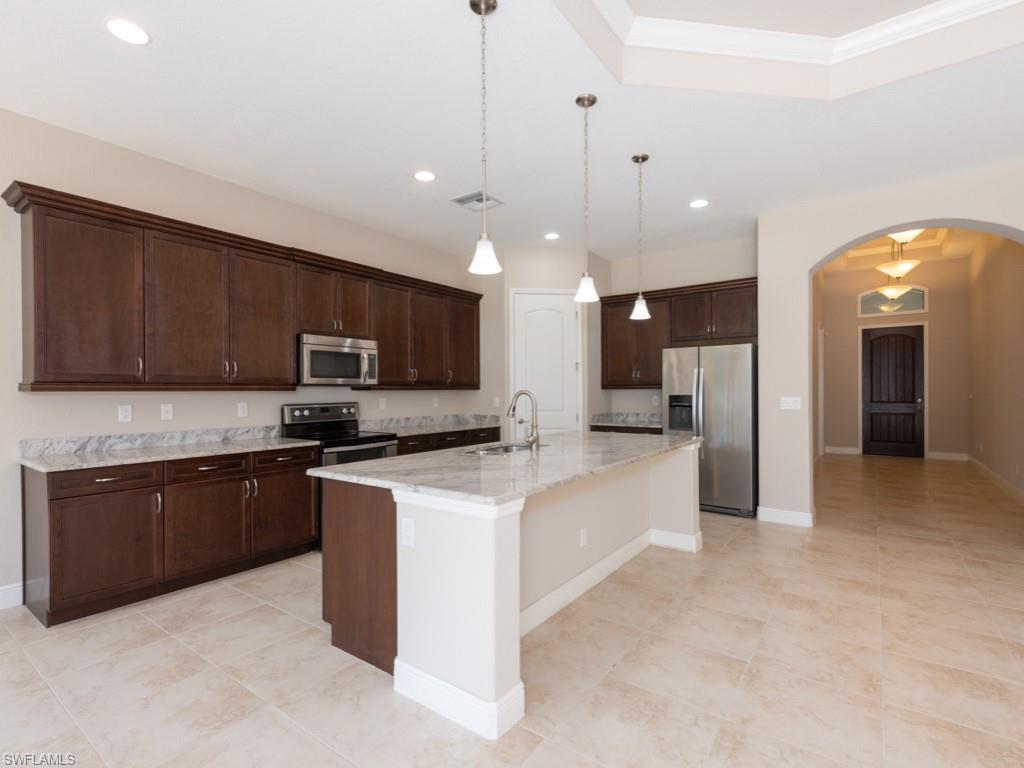 1638 Serrano Circle Naples, FL 34105 - Photo 6 of 23 a large kitchen with stainless steel appliances kitchen island granite countertop a stove sink and cabinets