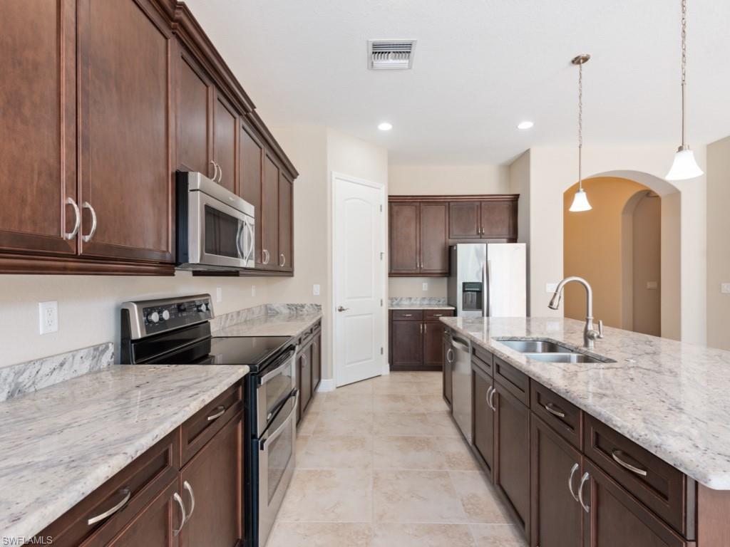 1638 Serrano Circle Naples, FL 34105 - Photo 7 of 23 a kitchen with stainless steel appliances granite countertop a sink stove microwave and cabinets