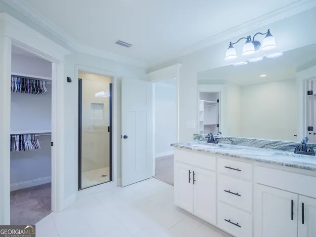 a spacious bathroom with a granite countertop sink a mirror and a shower