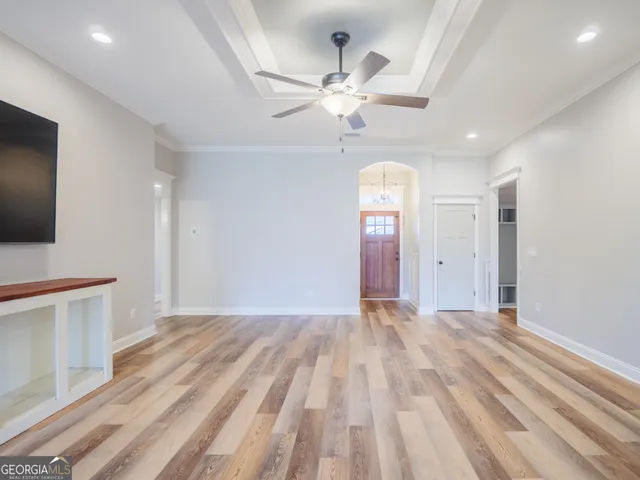 a view of an empty room with wooden floor and a window