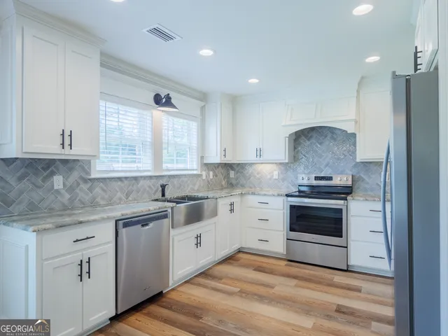 a kitchen with granite countertop white cabinets and stainless steel appliances
