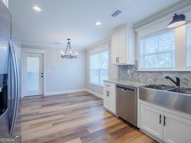 a kitchen with granite countertop a sink cabinets stainless steel appliances and window