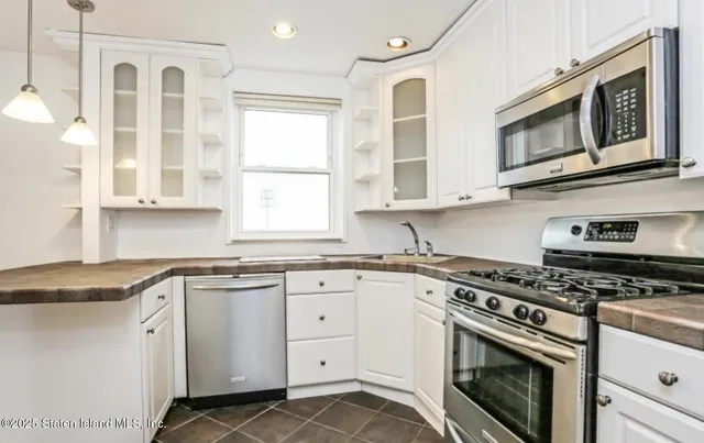 a kitchen with granite countertop white cabinets stainless steel appliances and a sink