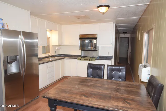 a kitchen with stainless steel appliances granite countertop a refrigerator a sink dishwasher a stove with white cabinets and wooden floor