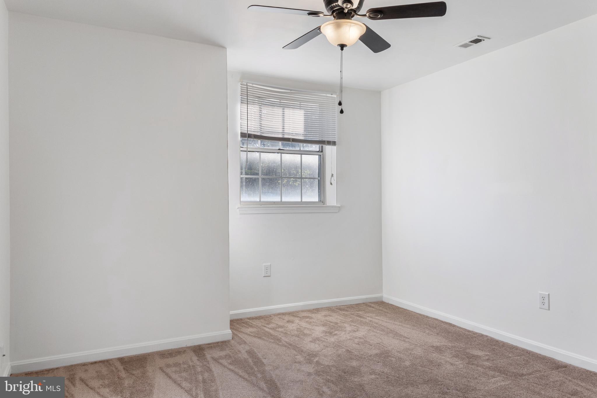 103 Three Coin Way, Unit 104 Glen Burnie, MD 21060 - Photo 11 of 19 an empty room with a chandelier fan and kitchen view