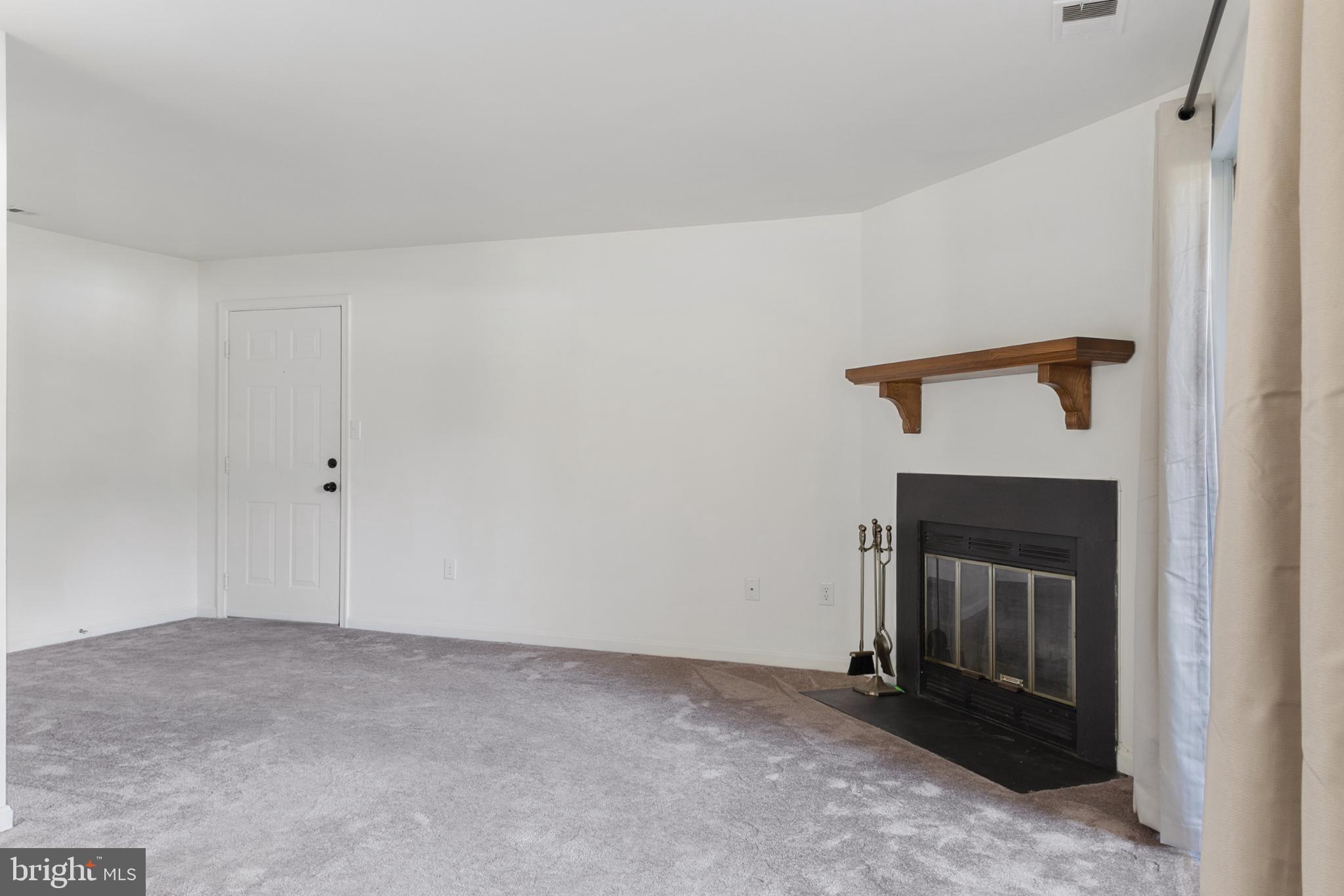 103 Three Coin Way, Unit 104 Glen Burnie, MD 21060 - Photo 4 of 19 a view of an empty room with a fireplace