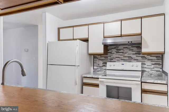 a kitchen with granite countertop white cabinets and white appliances