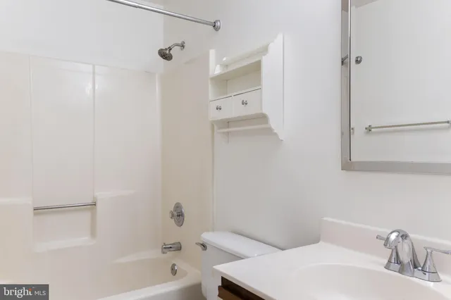 an empty room with a chandelier fan and kitchen view