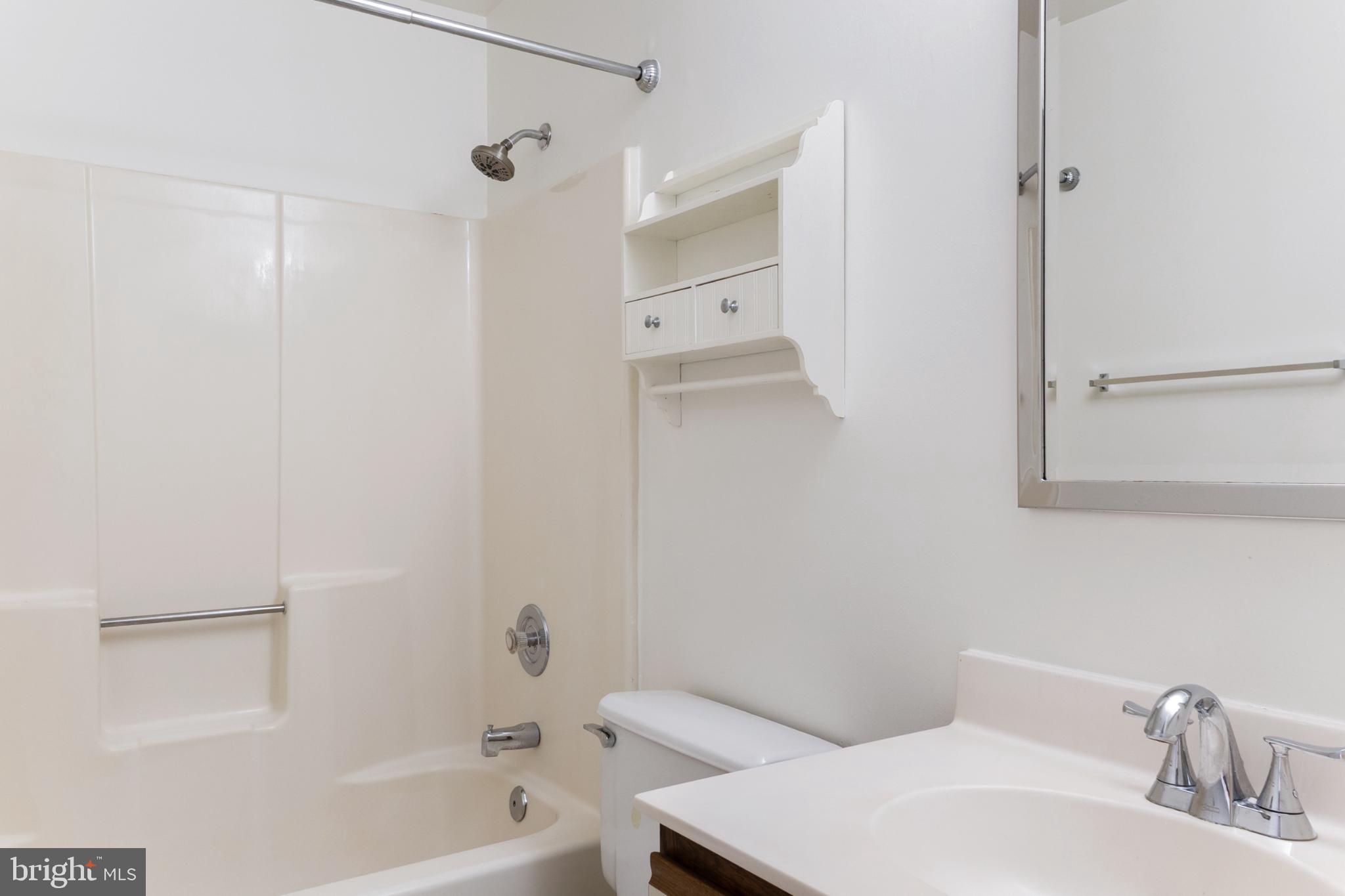 103 Three Coin Way, Unit 104 Glen Burnie, MD 21060 - Photo 10 of 19 a bathroom with a bathtub shower sink vanity and a toilet