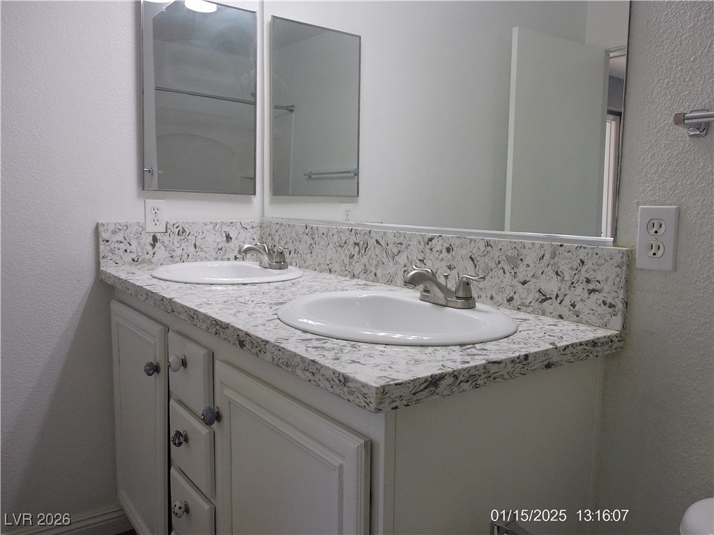 7332 Ribbon Ridge Avenue Las Vegas, NV 89129 - Photo 17 of 28 Bathroom featuring a textured wall and double vanity