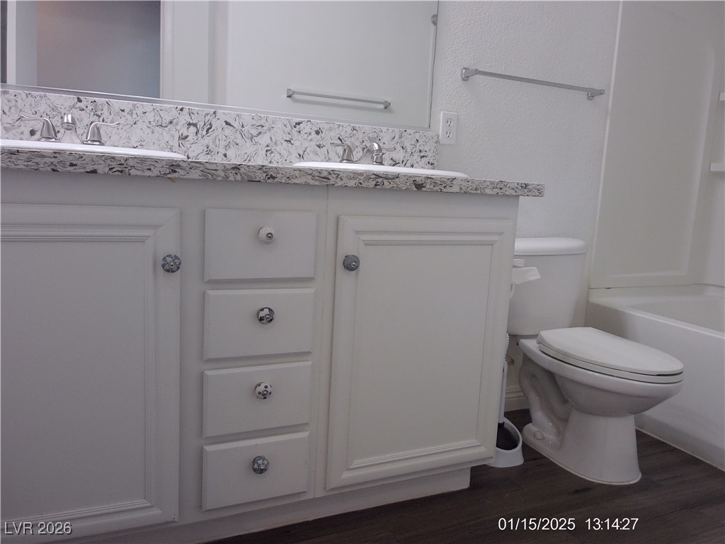 7332 Ribbon Ridge Avenue Las Vegas, NV 89129 - Photo 18 of 28 Bathroom featuring double vanity, dark wood-type flooring, and shower / washtub combination
