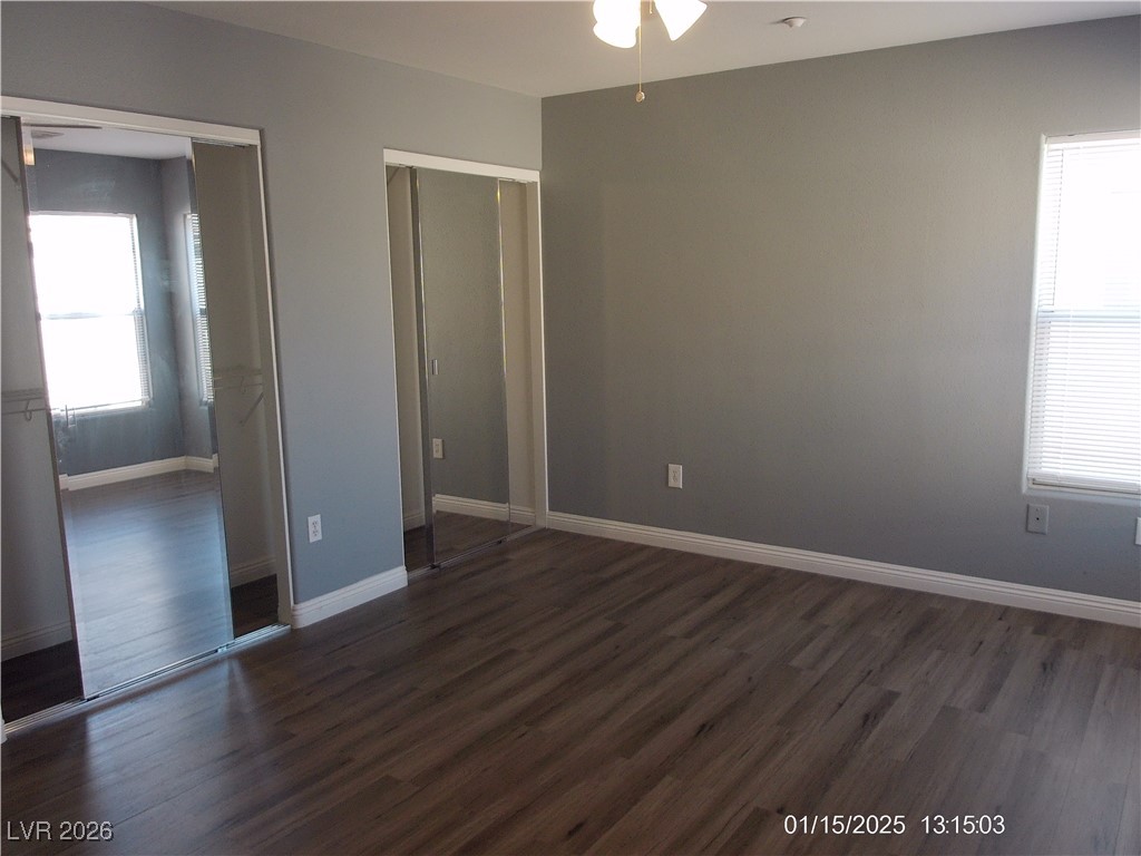 7332 Ribbon Ridge Avenue Las Vegas, NV 89129 - Photo 20 of 28 Unfurnished bedroom with multiple windows, dark wood finished floors, and a ceiling fan