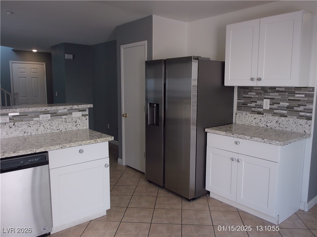 7332 Ribbon Ridge Avenue Las Vegas, NV 89129 - Photo 4 of 28 Kitchen with appliances with stainless steel finishes, light stone countertops, tasteful backsplash, and white cabinets