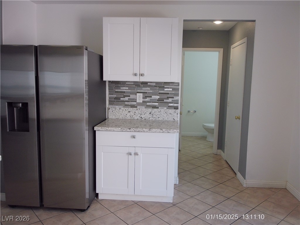 7332 Ribbon Ridge Avenue Las Vegas, NV 89129 - Photo 5 of 28 Kitchen with stainless steel fridge, white cabinetry, backsplash, and light tile patterned floors