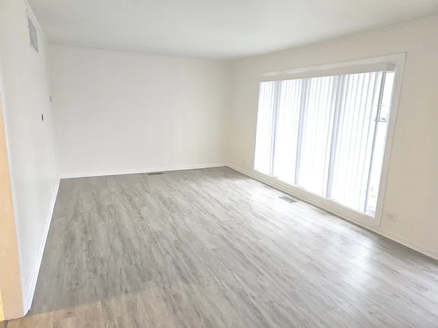 an empty room with wooden floor and windows with curtains view