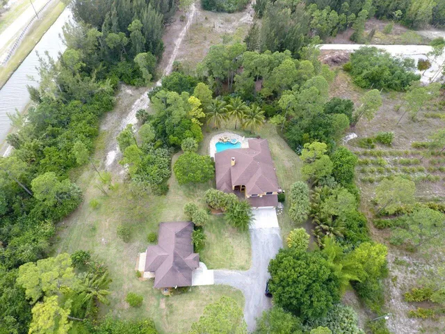 an aerial view of residential house with outdoor space and trees all around