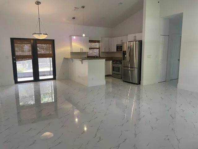 a kitchen with stainless steel appliances kitchen island granite countertop a refrigerator a stove a microwave and a sink