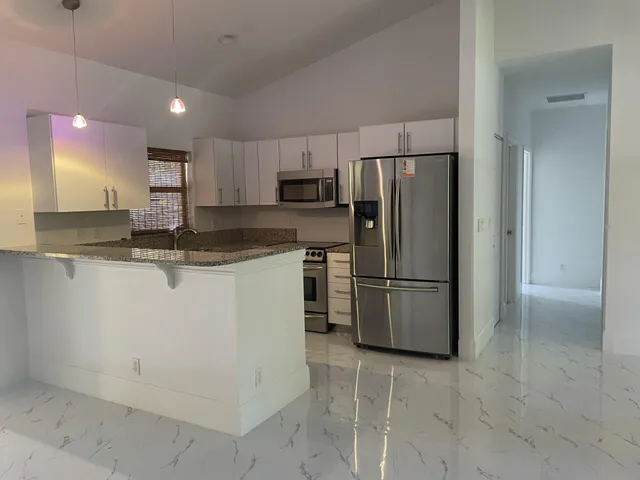 a kitchen with stainless steel appliances granite countertop a refrigerator sink and stove