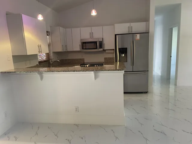 a kitchen with a sink a refrigerator and cabinets