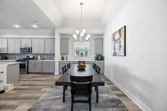 a kitchen with a dining table chairs and refrigerator