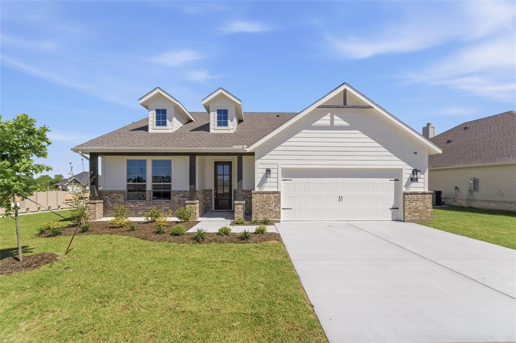 1221 Sabine River Lane Springtown, TX 76082 - Photo 3 of 25 View of front facade featuring a front lawn, a garage, covered porch, driveway, and brick siding