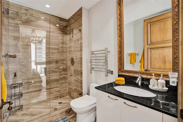 a bathroom with a granite countertop sink a toilet a mirror and shower