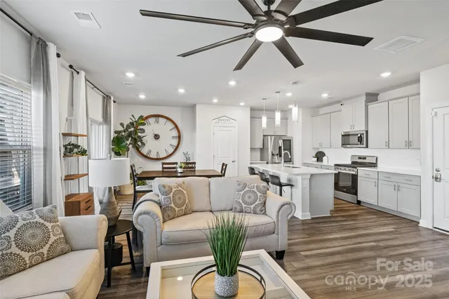 a kitchen with stainless steel appliances a stove a sink a microwave a refrigerator white cabinets and wooden floor