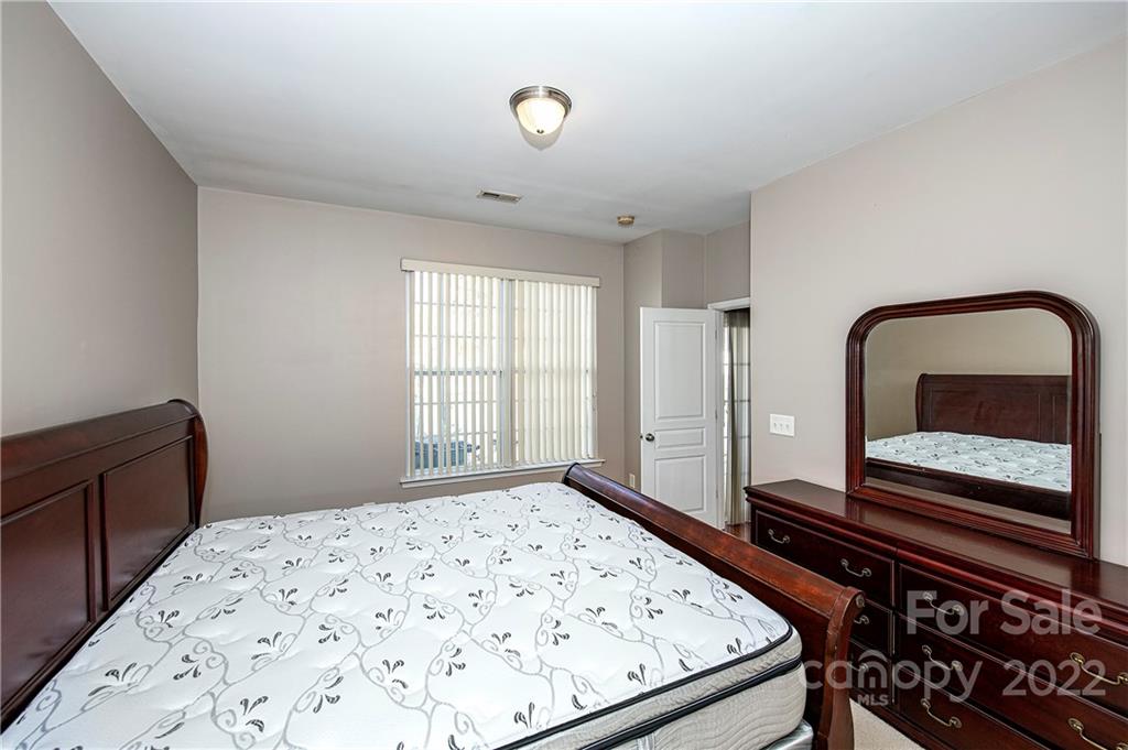 949 Copperstone Lane, Unit 203 Fort Mill, SC 29708 - Photo 8 of 19 a bedroom with a bed and a dresser with wooden floor