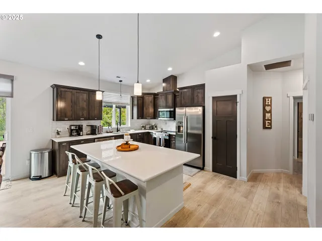 a kitchen with stainless steel appliances kitchen island granite countertop a refrigerator a stove a microwave oven a sink with island and chairs