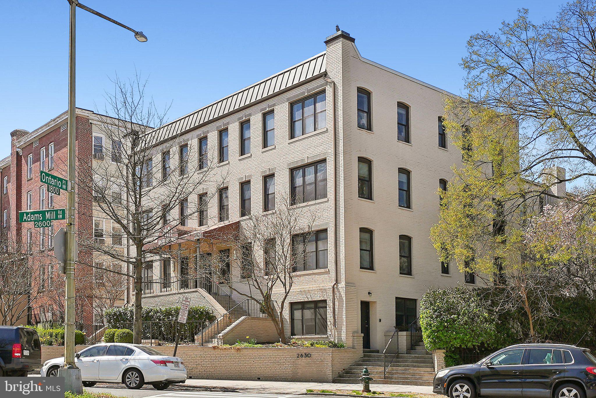 2630 Adams Mill Road Northwest, Unit 303 Washington, DC 20009 - Photo 18 of 18 a front view of a building with lot of cars and trees