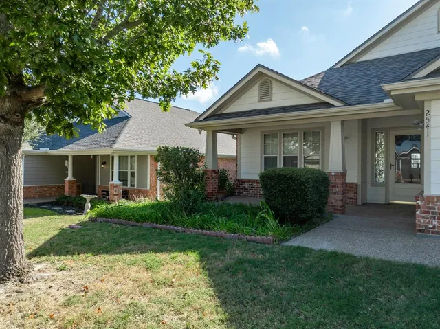 a view of a house with a yard and plants with table and chairs under an umbrella