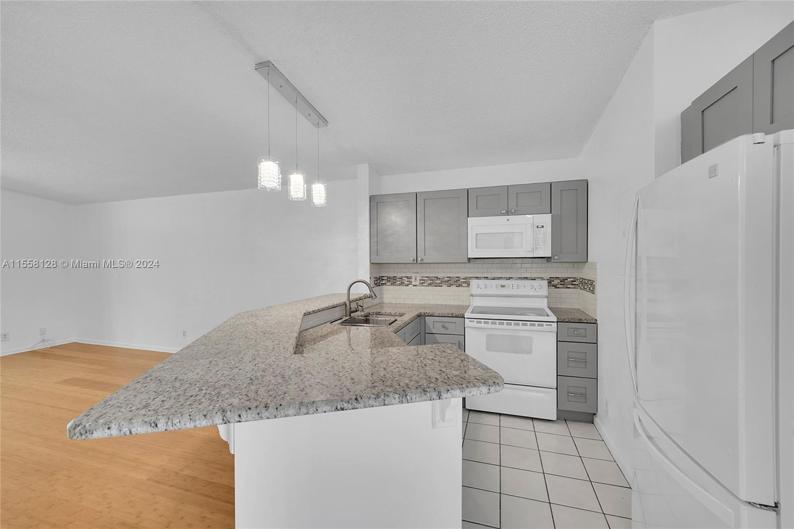 616 Woodgate Circle, Unit D Sunrise, FL 33326 - Photo 8 of 15 a kitchen with granite countertop a sink a stove a refrigerator and white cabinets