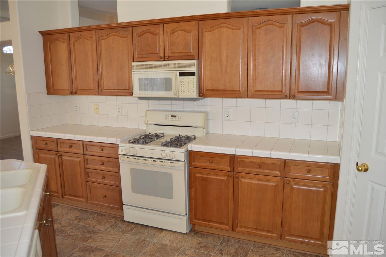 1170 Broadview Court Reno, NV 89521 - Photo 3 of 25 a kitchen with stainless steel appliances granite countertop a sink dishwasher a washer and dryer with wooden cabinets