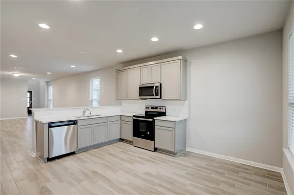 a large kitchen with stainless steel appliances granite countertop a refrigerator and a sink