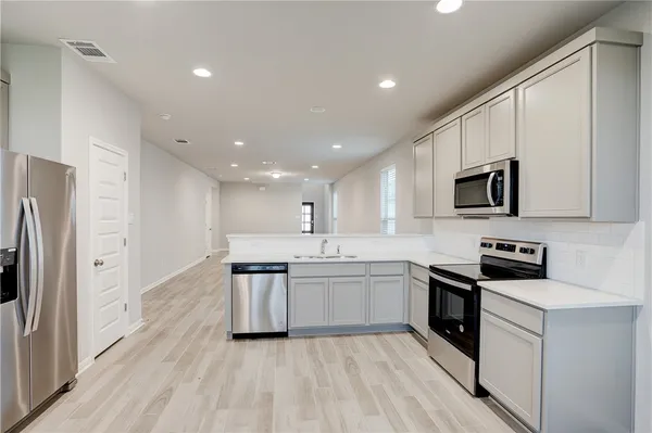 a kitchen with white cabinets and wooden floor