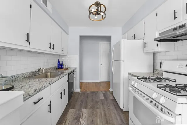 a kitchen with granite countertop a sink stove and cabinets
