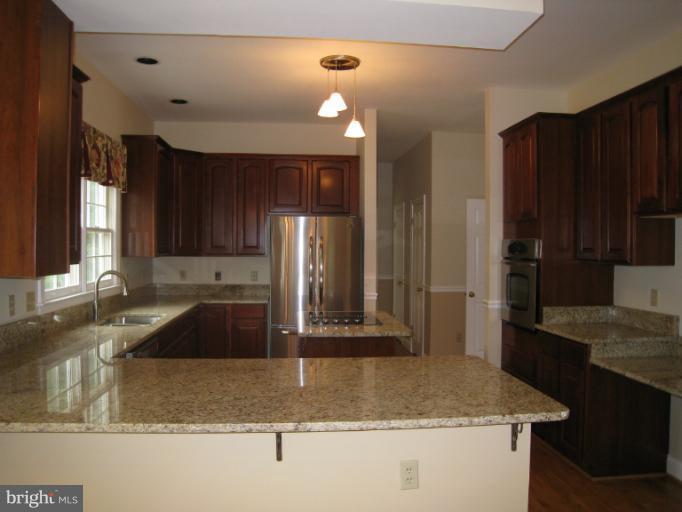 10118 Colvin Run Road Great Falls, VA 22066 - Photo 11 of 26 a kitchen with kitchen island granite countertop a sink a counter top space and cabinets