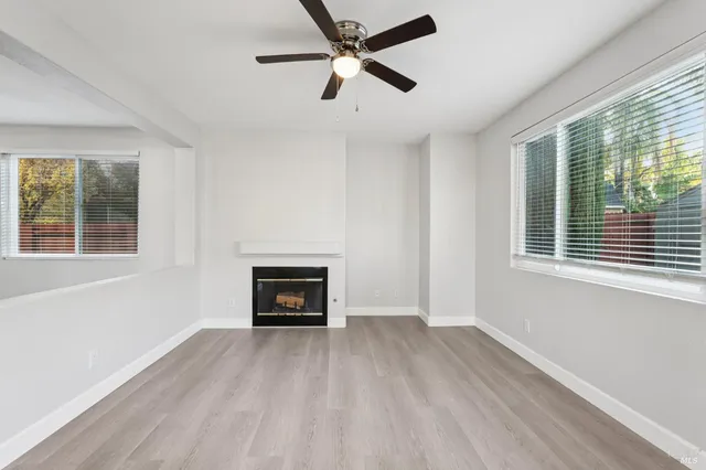 a view of empty room with wooden floor and fan