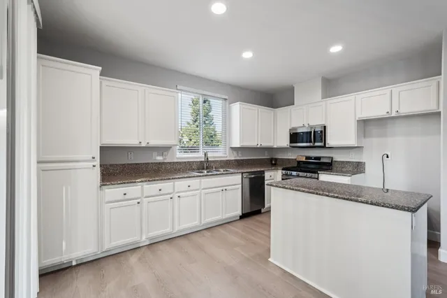 a kitchen with granite countertop white cabinets and white appliances