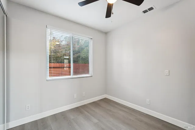 an empty room with a window and a ceiling fan