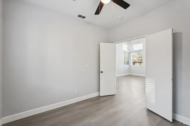 an empty room with windows and ceiling fan