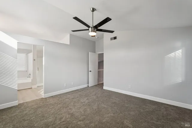 an empty room with a ceiling fan and window