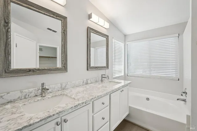 a bathroom with a granite countertop sink a mirror bathtub and shower